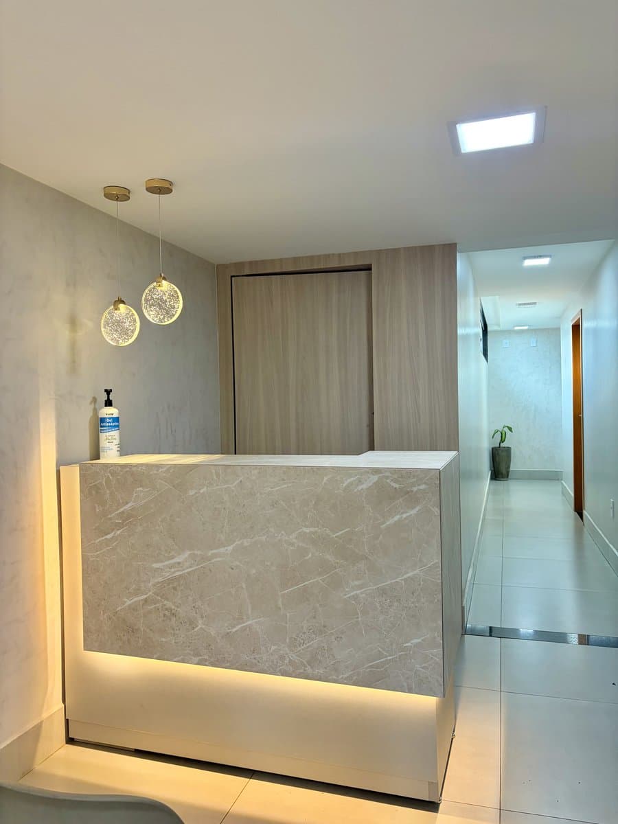 Recepção do consultório com balcão em mármore e iluminação elegante